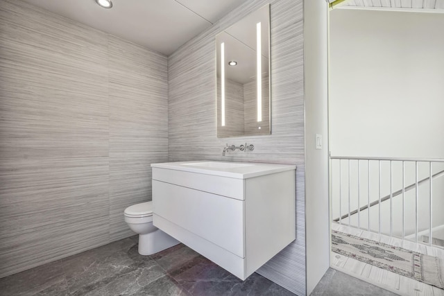 bathroom with recessed lighting, vanity, toilet, and tile walls