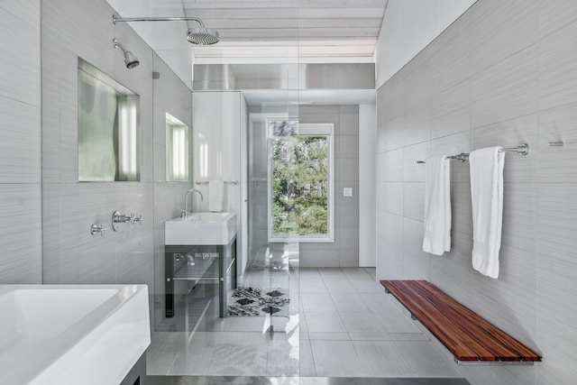 full bath with tile patterned flooring, tile walls, a shower, and vanity