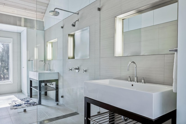 bathroom with tile patterned flooring, tile walls, tiled shower, tasteful backsplash, and a sink