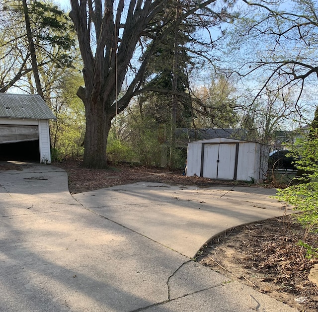 802 Dupont St, Flint, MI 48504 - view of patio featuring an outdoor structure, a storage unit, and a garage