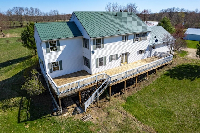rear view of property featuring a wooden deck, a lawn, and metal roof