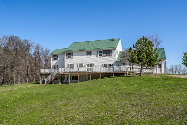 rear view of property featuring a wooden deck, stairway, a yard, and metal roof