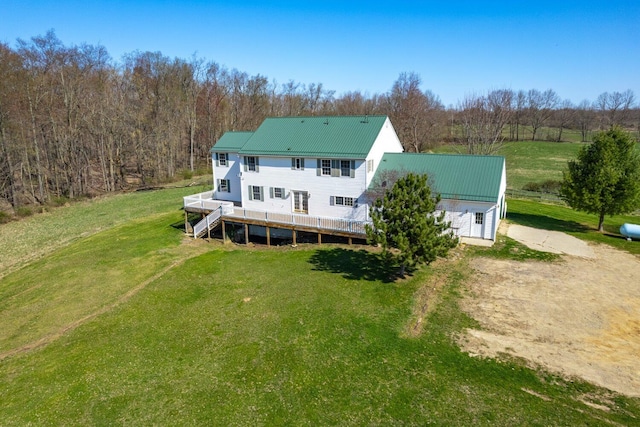 back of house with a wooden deck, a lawn, and metal roof
