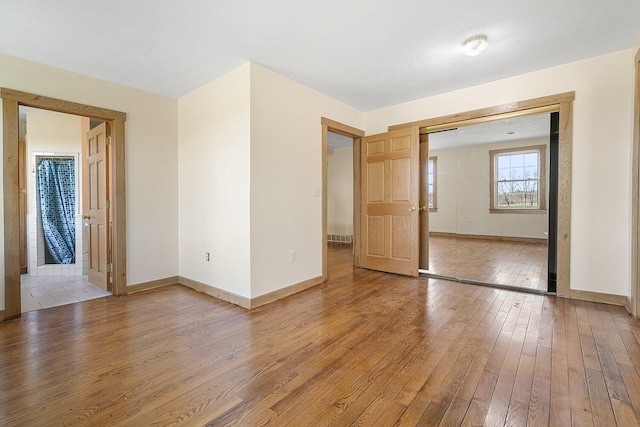 unfurnished room with baseboards and wood-type flooring