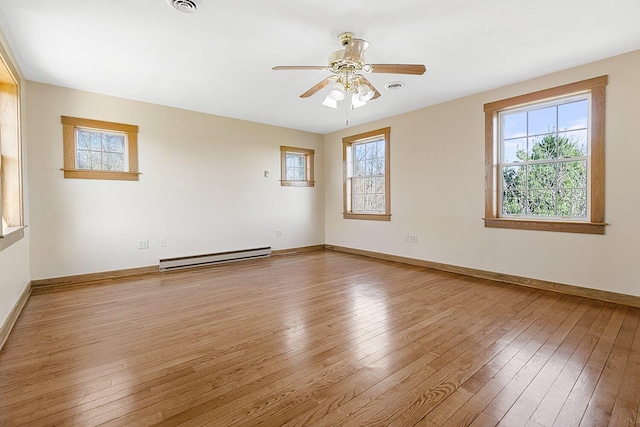 spare room featuring a baseboard radiator, a wealth of natural light, and light wood-style flooring