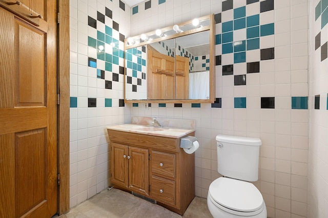 bathroom with toilet, vanity, and tile walls