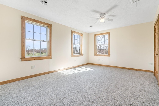 empty room with a textured ceiling, baseboards, visible vents, carpet, and a ceiling fan