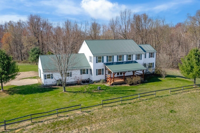 back of property featuring a wooden deck, a fenced backyard, a yard, and metal roof