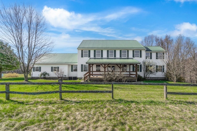 colonial inspired home featuring fence, a front yard, and metal roof