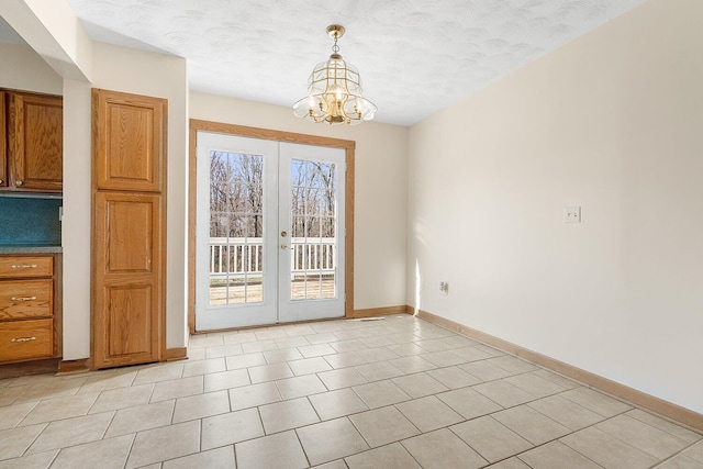 unfurnished dining area featuring light tile patterned floors, an inviting chandelier, french doors, and baseboards