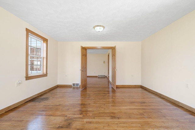 spare room with baseboards, visible vents, and light wood-style floors