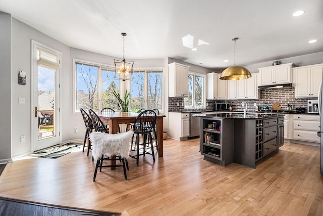 9037 Yorkshire Dr, Saline, MI 48176 - kitchen with stainless steel dishwasher, a sink, tasteful backsplash, dark countertops, and an inviting chandelier