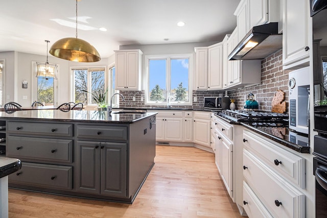 9037 Yorkshire Dr, Saline, MI 48176 - kitchen featuring white cabinets, gray cabinetry, under cabinet range hood, and backsplash