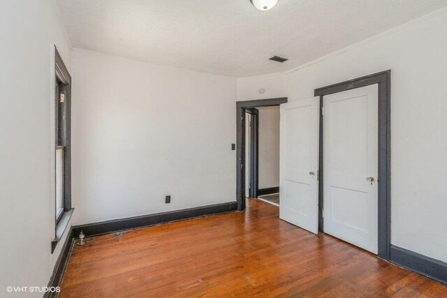 unfurnished bedroom featuring wood finished floors, visible vents, and baseboards