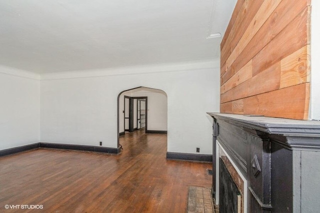 interior space with baseboards, arched walkways, ornamental molding, and wood finished floors