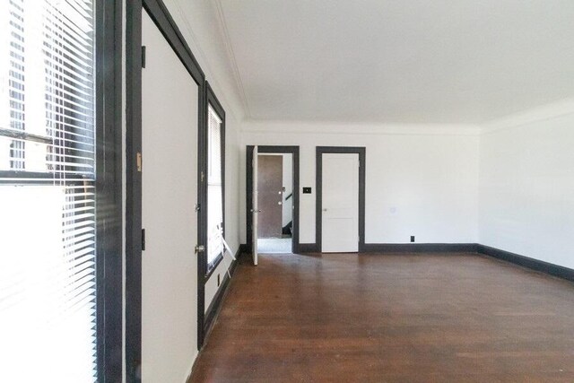 unfurnished room with crown molding, wood finished floors, and baseboards