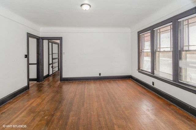 unfurnished room featuring dark wood-style flooring, baseboards, and a healthy amount of sunlight