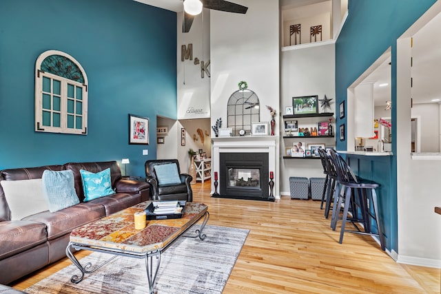 6240 Northridge Hills Dr, Brighton, MI 48116 - living room featuring a high ceiling, wood finished floors, a multi sided fireplace, a ceiling fan, and baseboards