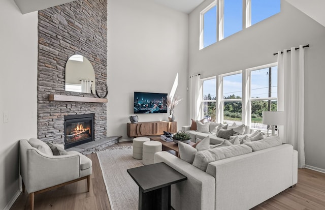 living room featuring baseboards, a high ceiling, wood finished floors, and a fireplace
