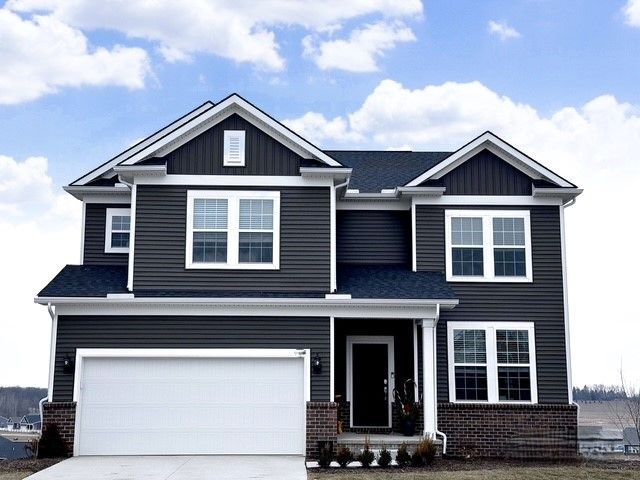 craftsman inspired home with board and batten siding, driveway, brick siding, and a garage