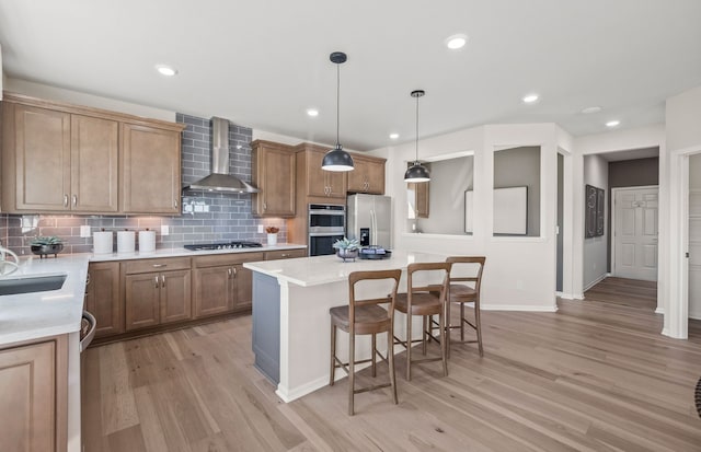 kitchen featuring light wood-type flooring, a breakfast bar, appliances with stainless steel finishes, and wall chimney range hood