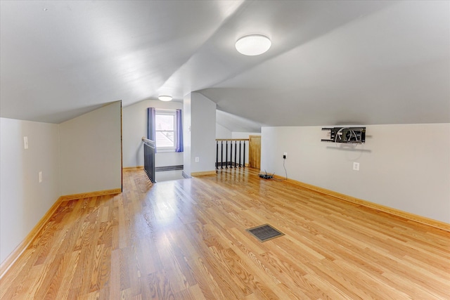 bonus room with light wood-style floors, lofted ceiling, and baseboards