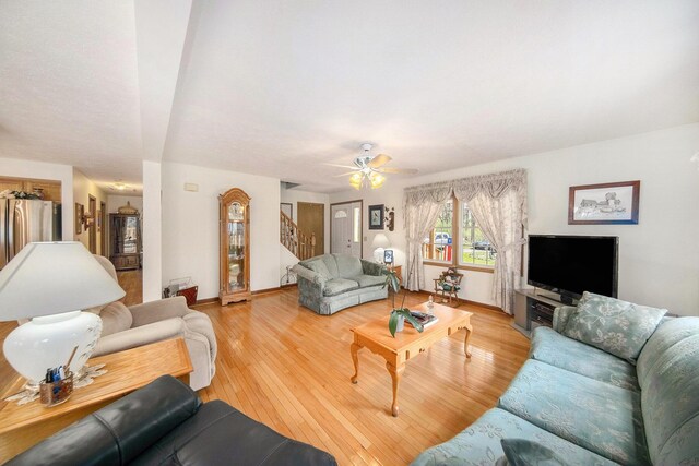 10500 Woodland Dr, Jerome, MI 49249 - living area with stairway, light wood finished floors, baseboards, and a ceiling fan