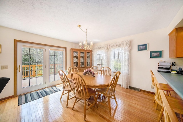 10500 Woodland Dr, Jerome, MI 49249 - dining space featuring light wood-style floors, visible vents, baseboards, and an inviting chandelier
