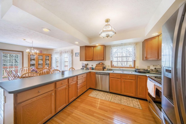 10500 Woodland Dr, Jerome, MI 49249 - kitchen featuring a peninsula, a sink, a chandelier, pendant lighting, and appliances with stainless steel finishes