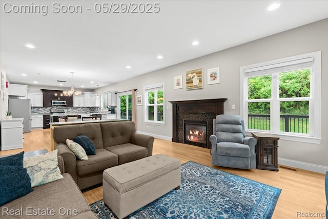 9327 Van Antwerp Rd, Brighton, MI 48116 - living room with healthy amount of natural light, a glass covered fireplace, recessed lighting, and light wood-style floors