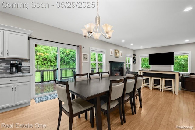 9327 Van Antwerp Rd, Brighton, MI 48116 - dining room featuring light wood-type flooring, a chandelier, healthy amount of natural light, recessed lighting, and a premium fireplace