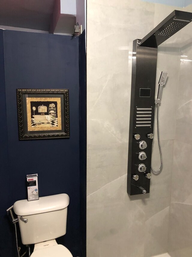 full bathroom featuring a tile shower and toilet
