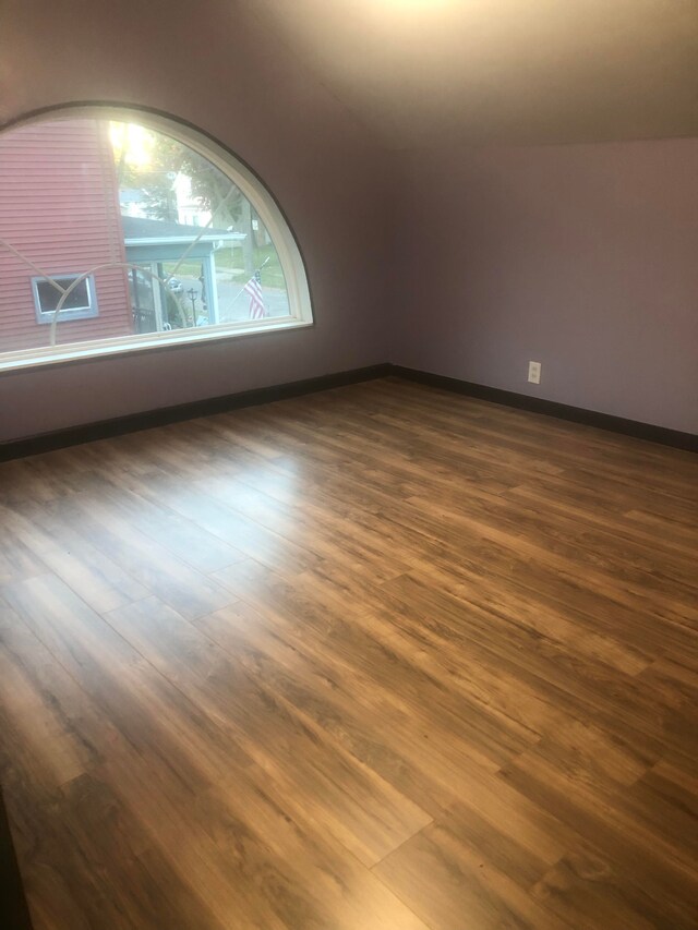 bonus room with baseboards and dark wood-style floors