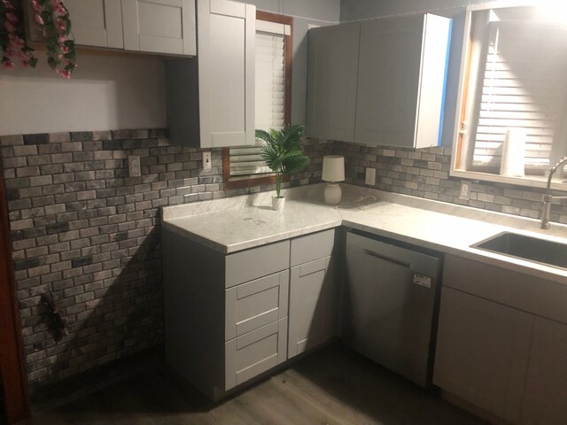kitchen with decorative backsplash, stainless steel dishwasher, light countertops, and a sink