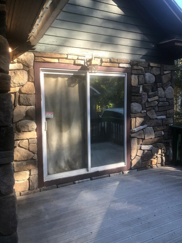 doorway to property with stone siding and a deck