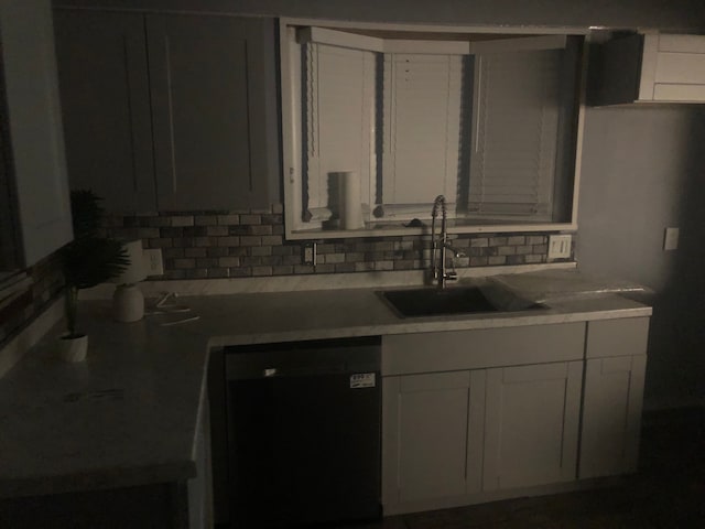 kitchen with white cabinets, a sink, decorative backsplash, dishwashing machine, and light countertops