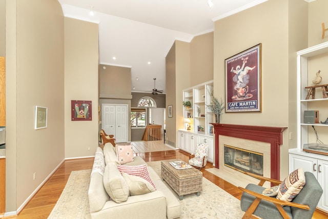 70 Chestnut Ct, Chelsea, MI 48118 - living area with light wood finished floors, a fireplace, a ceiling fan, crown molding, and a towering ceiling