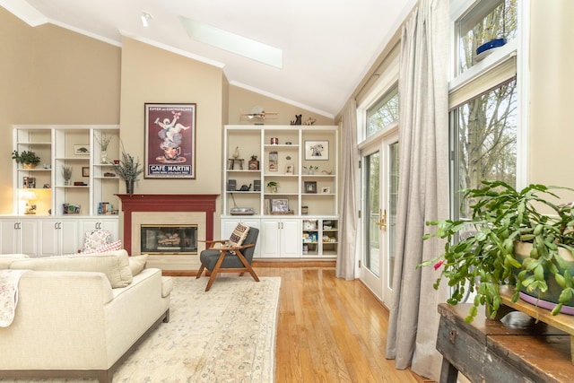 70 Chestnut Ct, Chelsea, MI 48118 - living area with lofted ceiling with skylight, ornamental molding, light wood-style flooring, and a glass covered fireplace