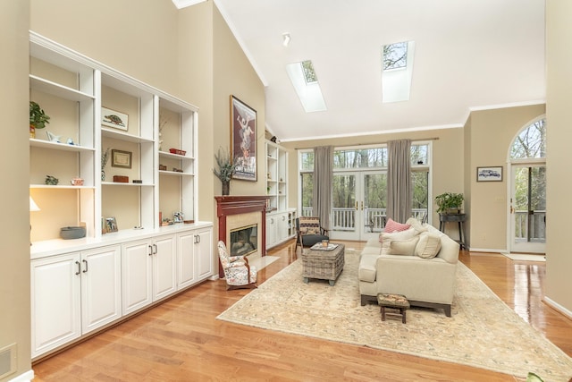 70 Chestnut Ct, Chelsea, MI 48118 - living area featuring a skylight, light wood-style flooring, a premium fireplace, high vaulted ceiling, and crown molding