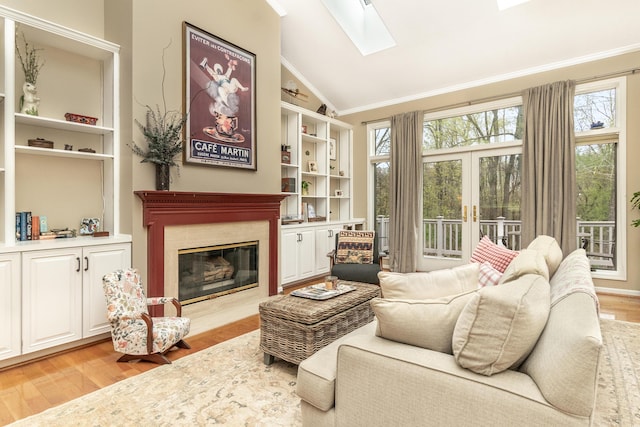 70 Chestnut Ct, Chelsea, MI 48118 - sitting room featuring a premium fireplace, vaulted ceiling with skylight, built in shelves, crown molding, and wood finished floors