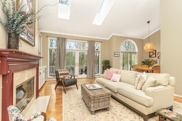 70 Chestnut Ct, Chelsea, MI 48118 - living area featuring a skylight, light wood-style flooring, a high end fireplace, high vaulted ceiling, and crown molding