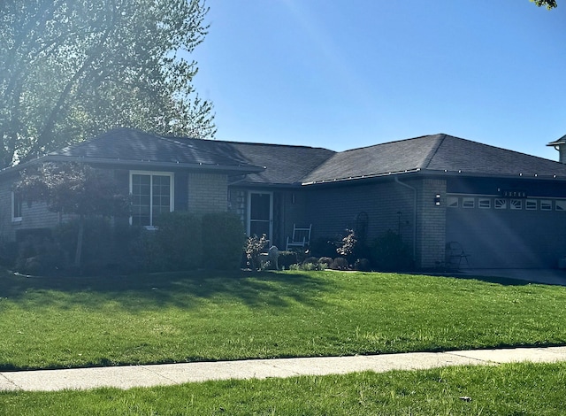 ranch-style house featuring brick siding, a garage, roof with shingles, and a front yard