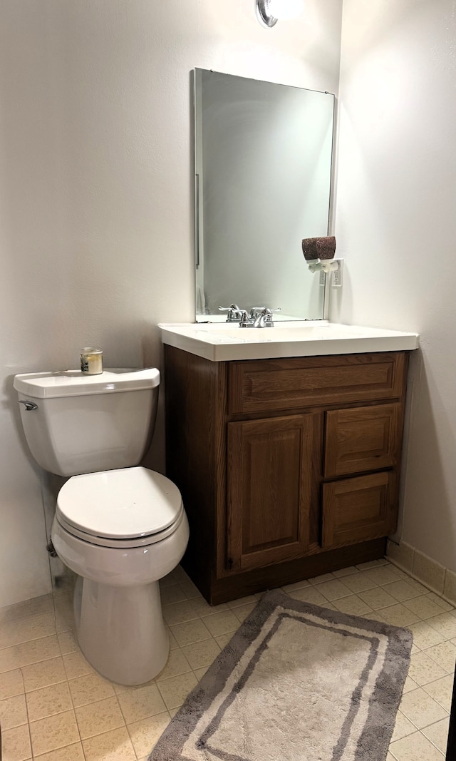half bathroom with toilet, tile patterned flooring, and vanity