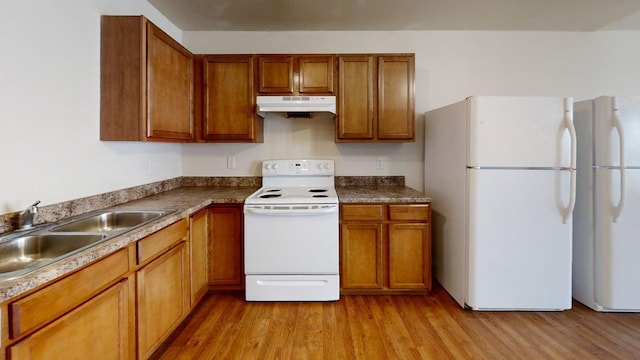 kitchen with a sink, light wood-type flooring, white appliances, brown cabinets, and under cabinet range hood