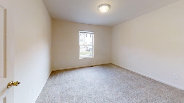 carpeted spare room featuring baseboards and visible vents