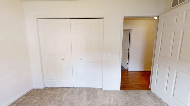 unfurnished bedroom featuring baseboards, a closet, visible vents, and carpet