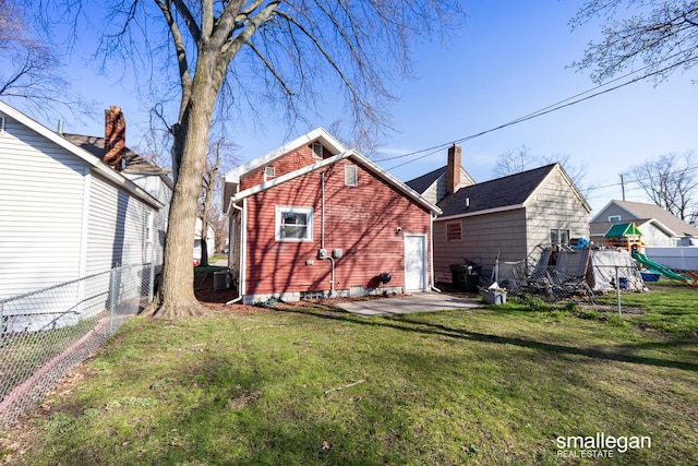 back of house featuring a fenced backyard, a yard, a patio, and a playground