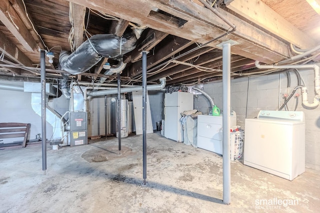 unfinished below grade area featuring washing machine and dryer, water heater, heating unit, and freestanding refrigerator