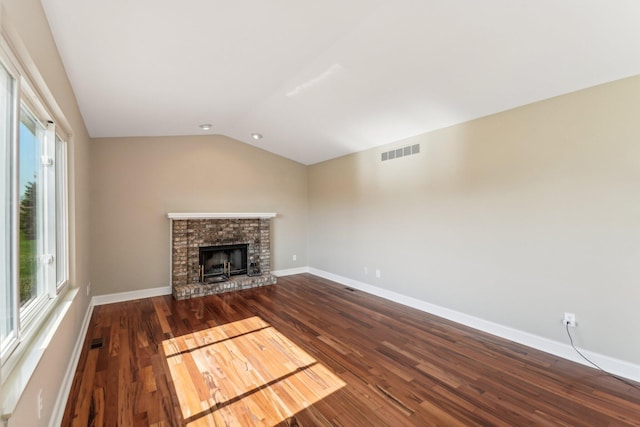 4658 White Pine Ct, Ypsilanti, MI 48197 - unfurnished living room featuring baseboards, lofted ceiling, dark wood-style flooring, a brick fireplace, and visible vents