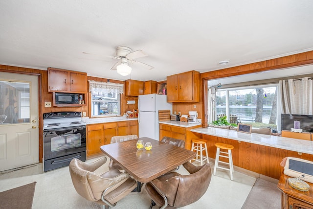 kitchen featuring black appliances, brown cabinets, a healthy amount of sunlight, and light countertops
